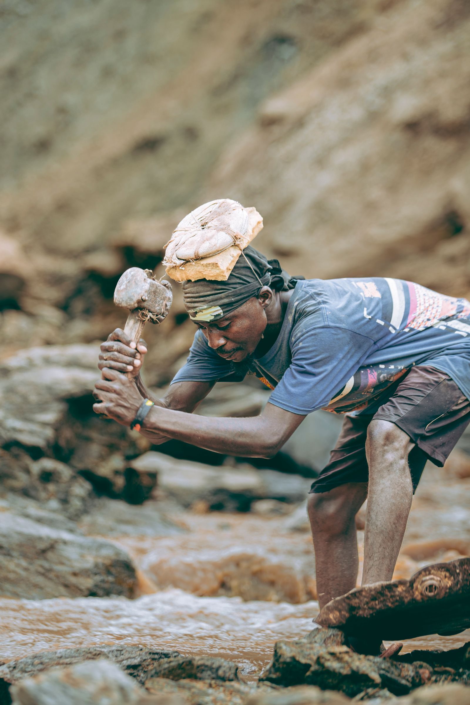Mineur brisant manuellement la roche pour extraire le minerai à la main